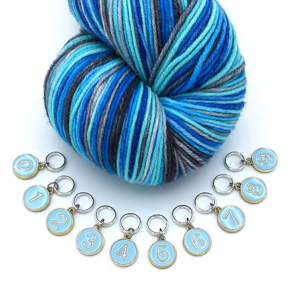 Set of ten blue on gold-toned number charm ring stitch markers with variegated yarn in blue colours for knitting by Pretty Warm Designs
