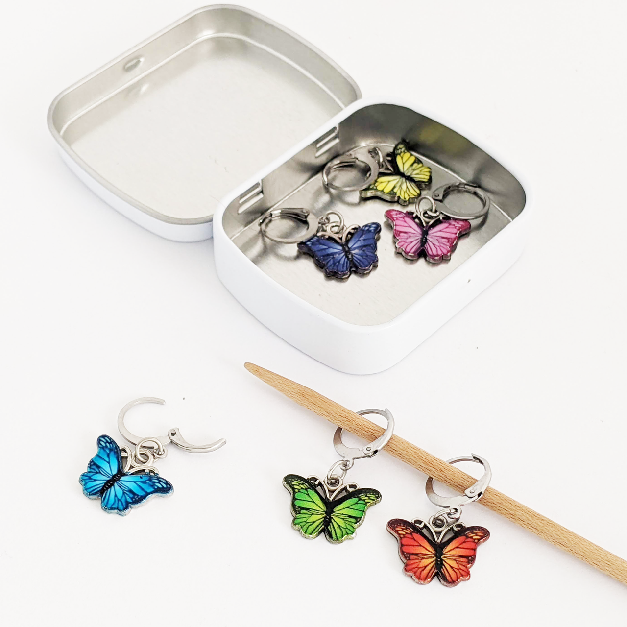 Set of six enamel butterfly charm crochet locking stitch markers in red, yellow, green, blue, pink and purple with storage tin for crochet by Pretty Warm Designs