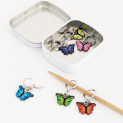 Set of six enamel butterfly charm crochet locking stitch markers in red, yellow, green, blue, pink and purple with storage tin for crochet by Pretty Warm Designs