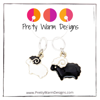 Package of two knitting stitch markers containing one black sheep and one white sheep ring marker attached to white cardstock with Pretty Warm Designs logo and text