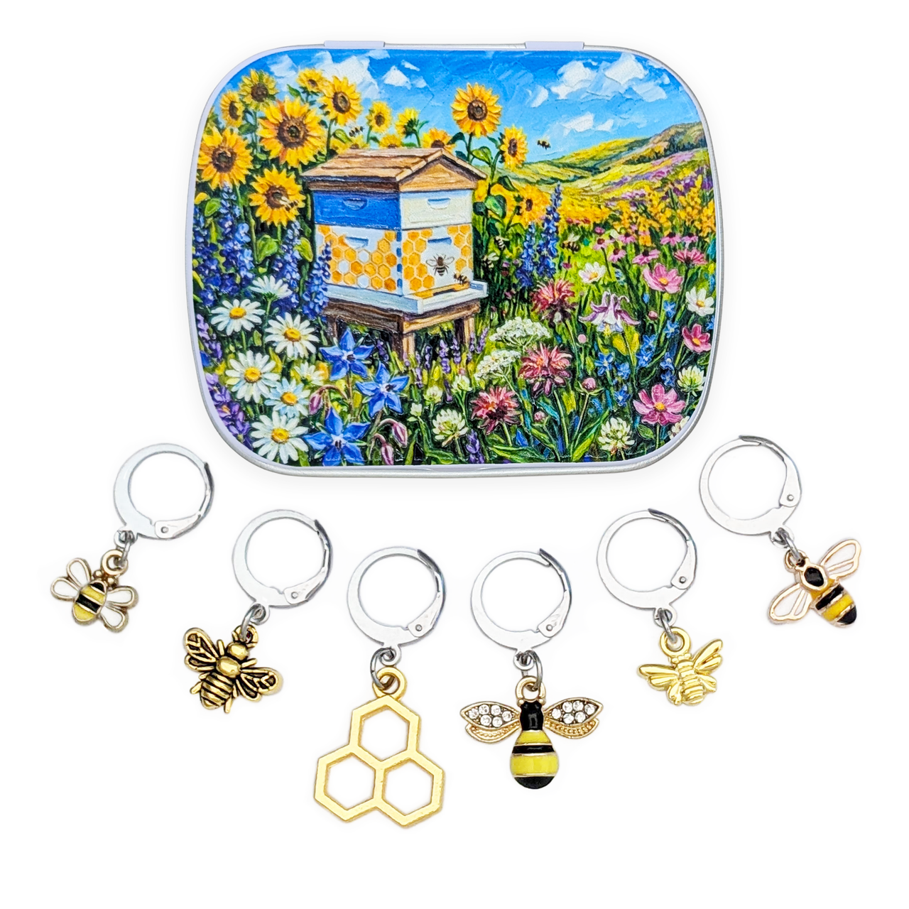 A bee-themed gift set featuring a square tin with a colorful sunflower and beehive illustration, plus five silver and gold locking stitch markers with charms shaped like bees and honeycomb, arranged on a white background.