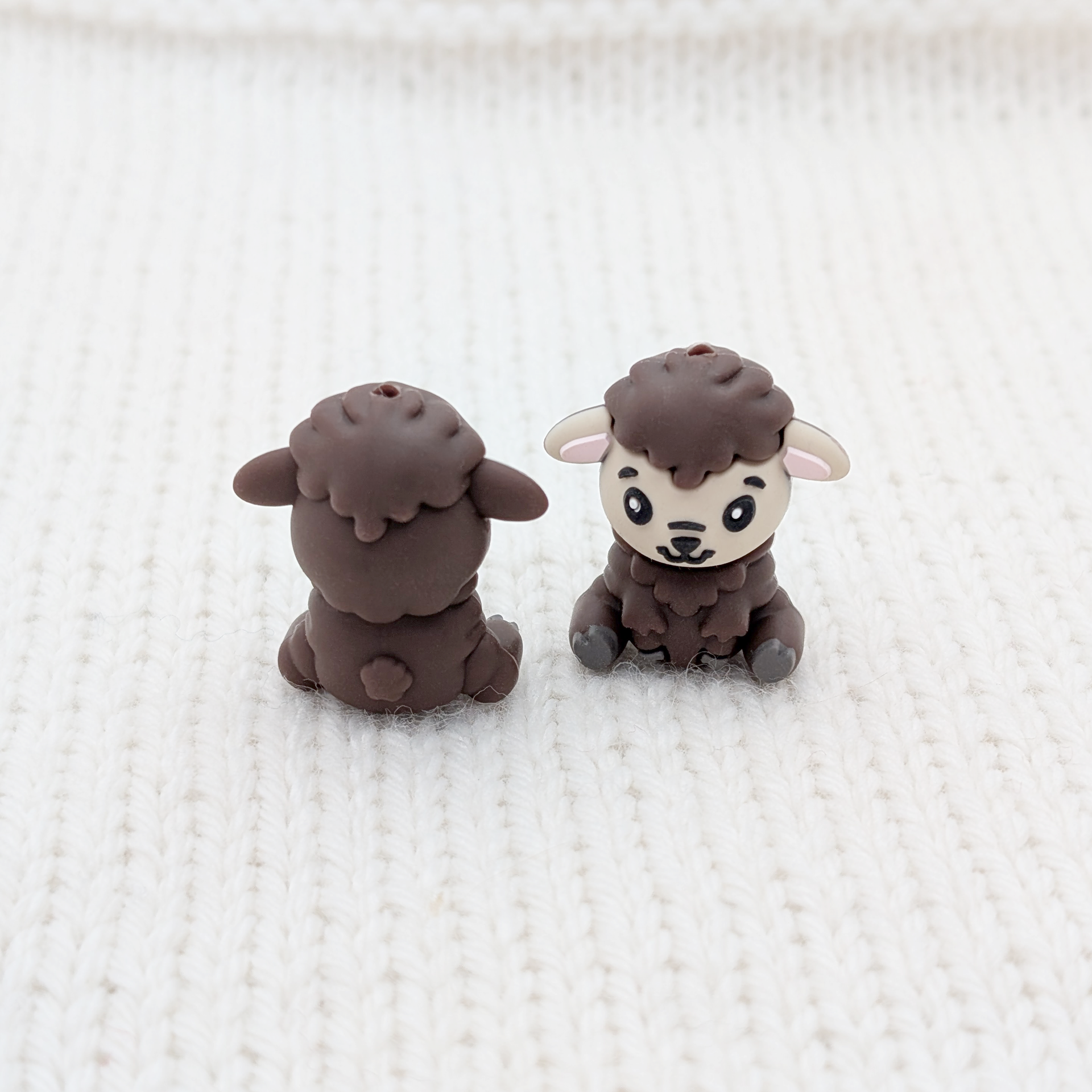 Front and back view of Mocha Feeling Sheepish sheep stitch stoppers on white knit fabric