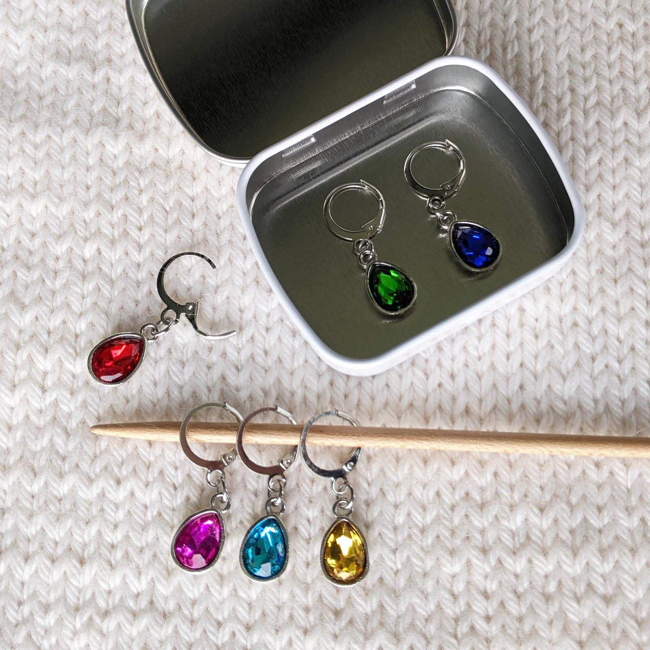 Crystal Jewels set of 6 gem coloured stitch holders with storage tin by Pretty Warm Designs shown on knitting needle