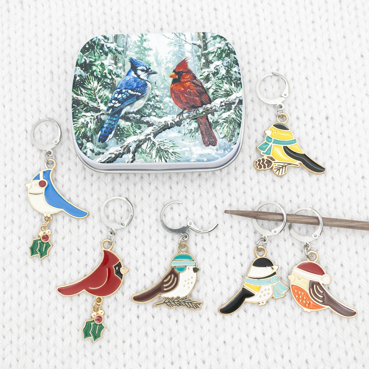 Christmas bird locking stitch markers beside the winter bird tin