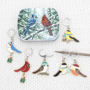 Christmas bird locking stitch markers beside the winter bird tin