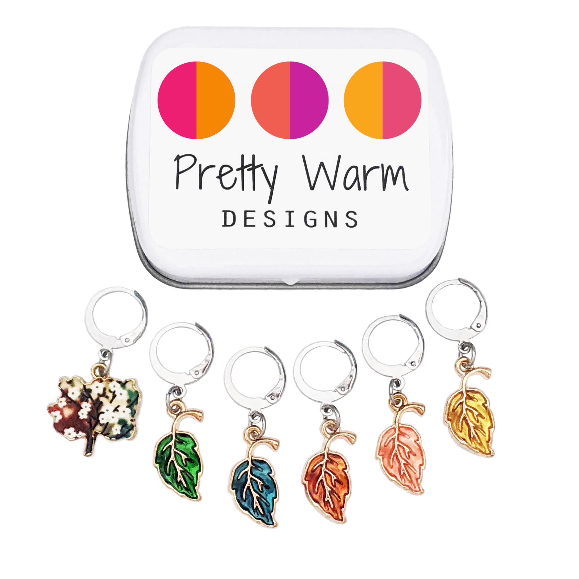 Set of 6 locking stitch markers with glossy enamel metal charms in the shape of leaves and a tree, shown with a white storage tin. Handmade by Pretty Warm Designs.