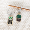 Set of two cactus themed locking stitch markers for crochet or knitting by Pretty Warm Designs shown on a knitting needle