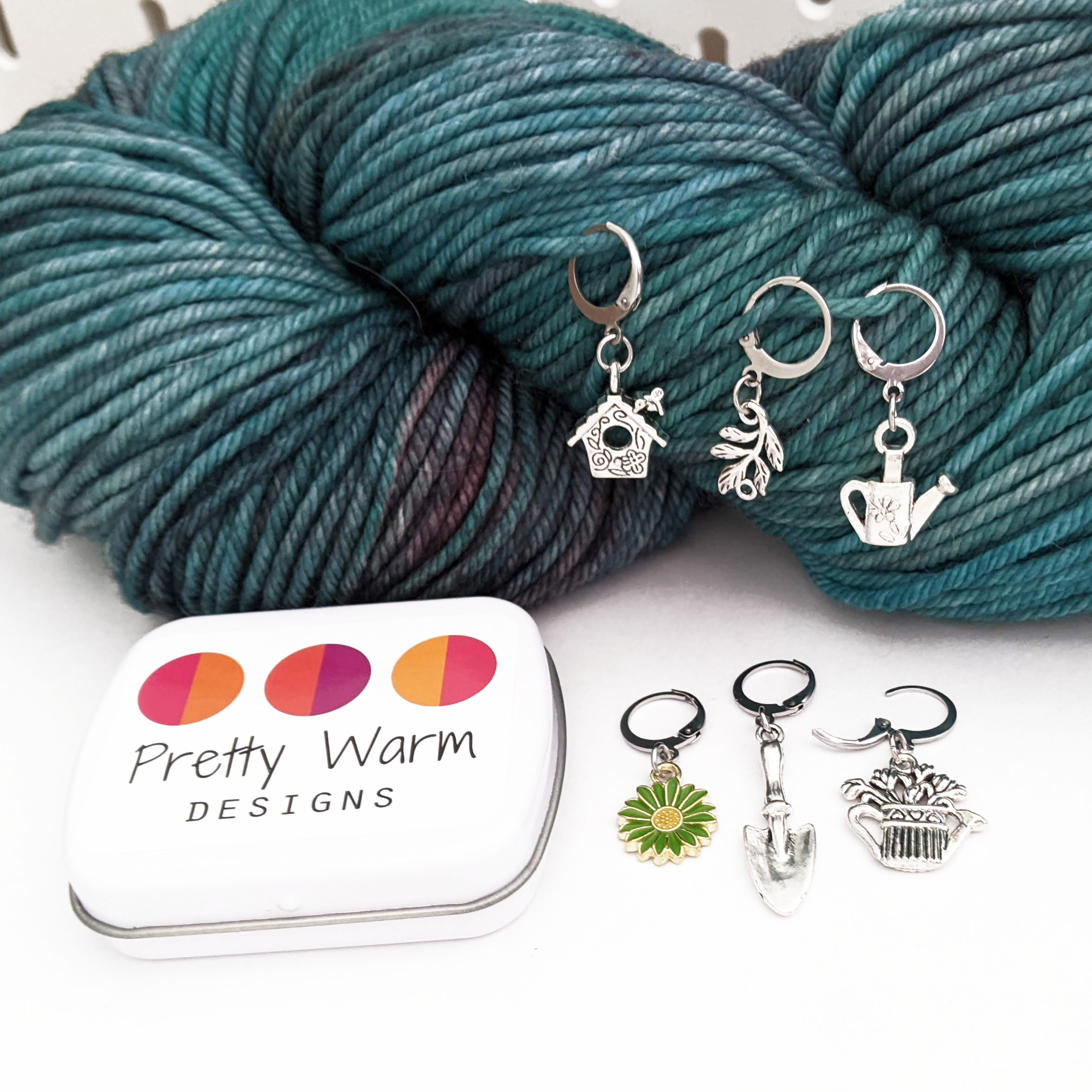 Set of one green and yellow enamel daisy and five antiqued silver alloy gardening themed locking stitch markers with a green worsted weight skein of yarn for crochet by Pretty Warm Designs Inc