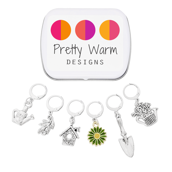 Set of one green and yellow enamel daisy and five antiqued silver alloy gardening themed locking stitch markers for crochet and decorative storage tin with logo by Pretty Warm Designs Inc