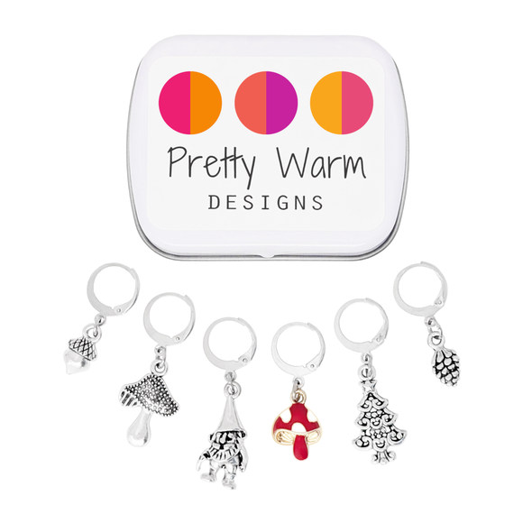Set of five antiqued silver charm crochet stitch markers and one enamel toadstool charm locking crochet stitch markers with decorative Pretty Warm Designs logo tin for crochet by Pretty Warm Designs