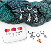 Set of five antiqued silver charm crochet stitch markers and one enamel toadstool charm locking crochet stitch markers with decorative Pretty Warm Designs logo tin for crochet by Pretty Warm Designs