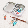 Set of 6 Removable stitch markers for crochet or knitting with multicoloured robot charms and storage tin. Shown on a knitting needle with opening clasp.