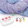 Rainbow Sparkle Crochet Stitch Markers, Set of 6 with storage tin. 6 different pride colors with a leverback clasp for knitter or crocheters. Shown attached to worsted weight yarn.