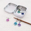 Tree of Life Stitch Marker set of 6 with storage tin, 6 different colours with lever-back clasps for crochet or knitters. Shown on Knitting needle.