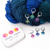 Tree of Life Stitch Marker set of 6 with storage tin, 6 different colours with lever-back clasps for crochet or knitters. Shown attached to worsted weight yarn.