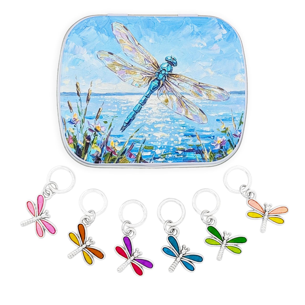 A square tin with rounded corners featuring a painted blue dragonfly over water, shown above five small dragonfly-shaped ring style stitch marker charms in different colors attached to silver rings on a white background.