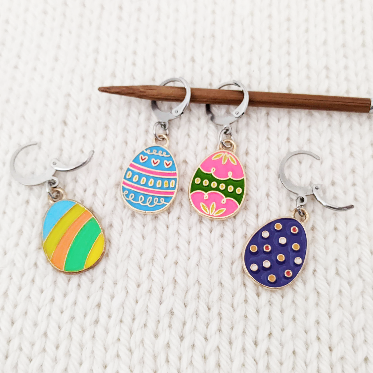 Set of 4 Easter egg themed removable stitch markers for crochet or knitting shown on a knitting needle