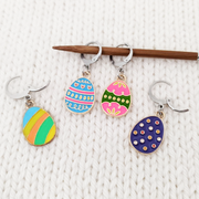 Set of 4 Easter egg themed removable stitch markers for crochet or knitting shown on a knitting needle