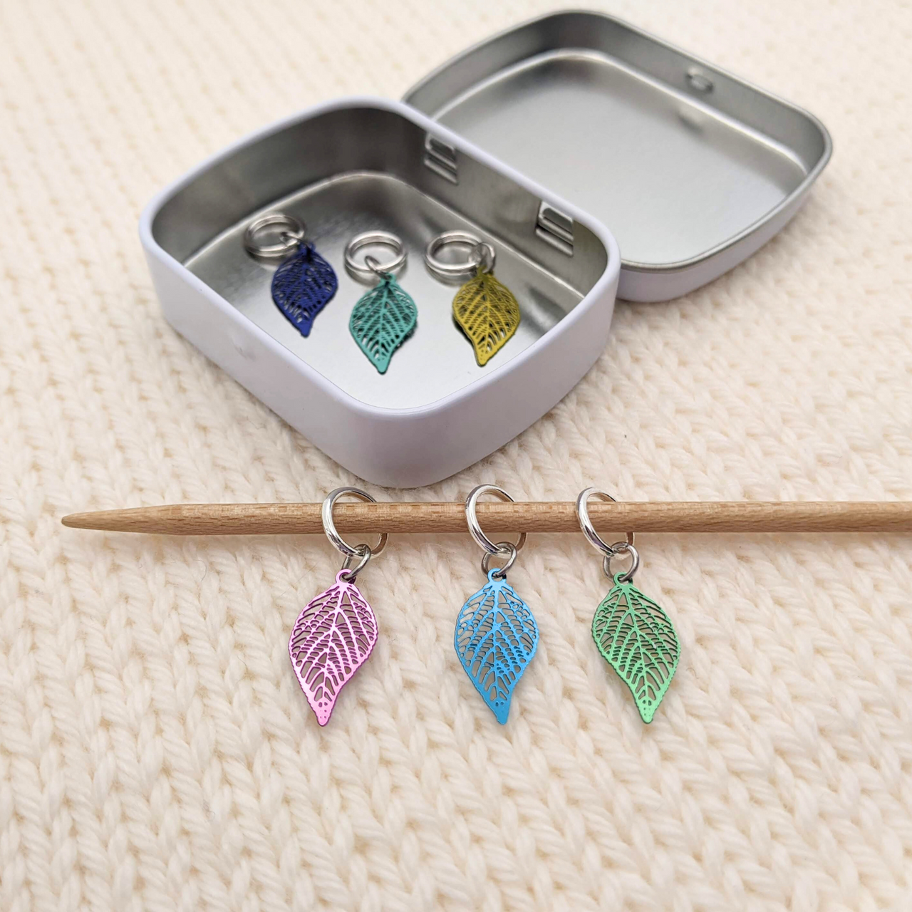Fallen Leaves Stitch Markers, Set of 6 with storage tin, shown on knitting needle