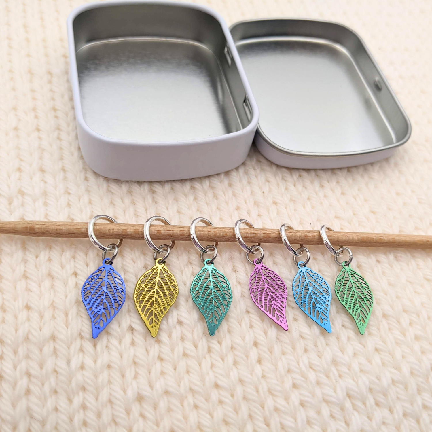 Fallen Leaves Stitch Markers, Set of 6 with storage tin, shown on knitting needle