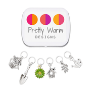 Set of one green and yellow enamel daisy and five antiqued silver alloy gardening themed snag free ring stitch markers for knitting and decorative storage tin with logo by Pretty Warm Designs Inc