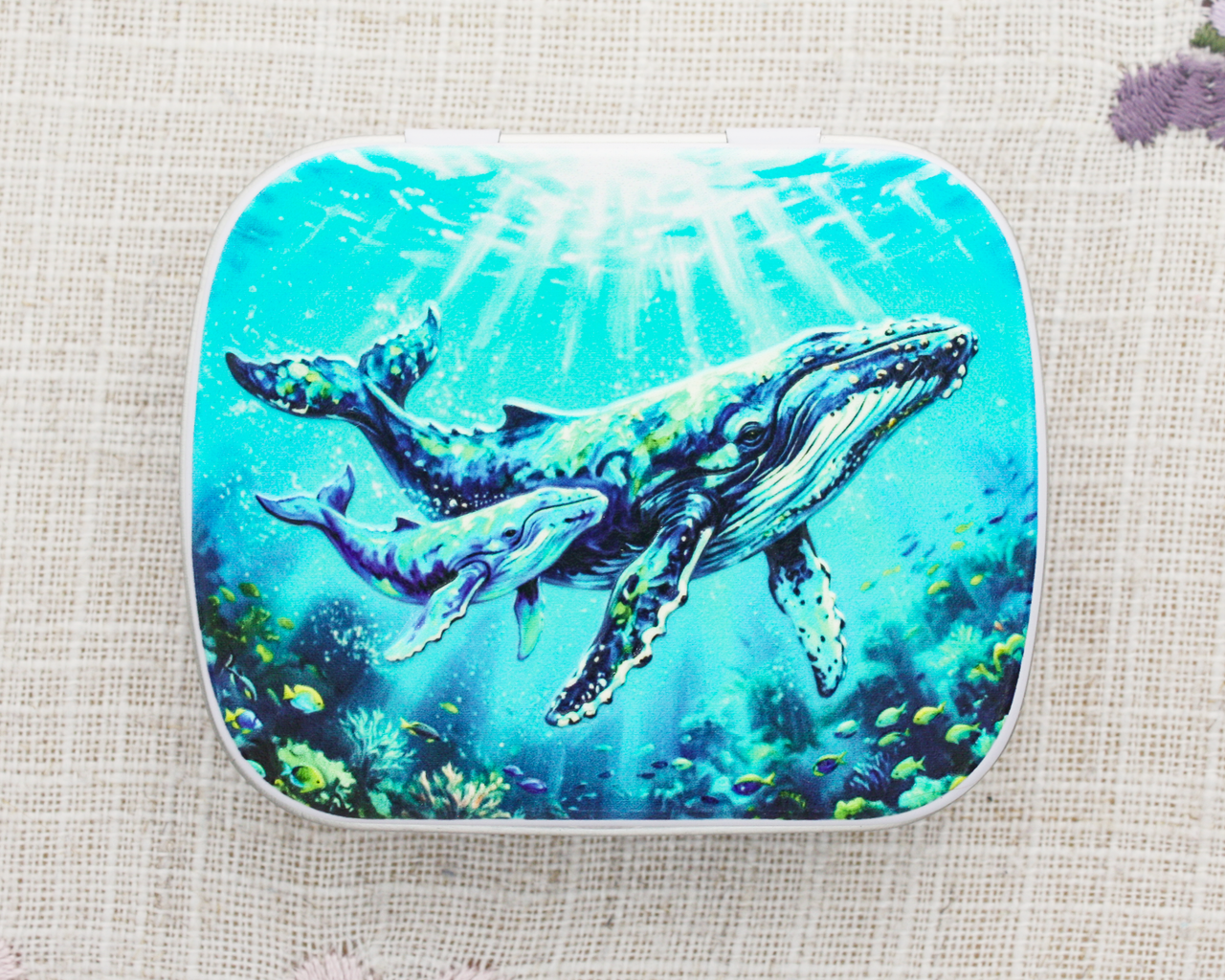 A hinged metal stitch marker notions tin featuring a humpback whale mother and calf
