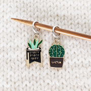 Set of two cactus themed stitch markers for knitting by Pretty Warm Designs shown on a knitting needle