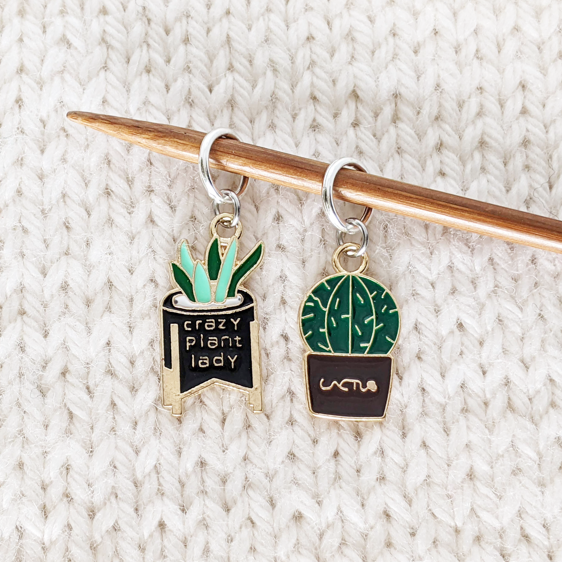 Set of two cactus themed stitch markers for knitting by Pretty Warm Designs shown on a knitting needle