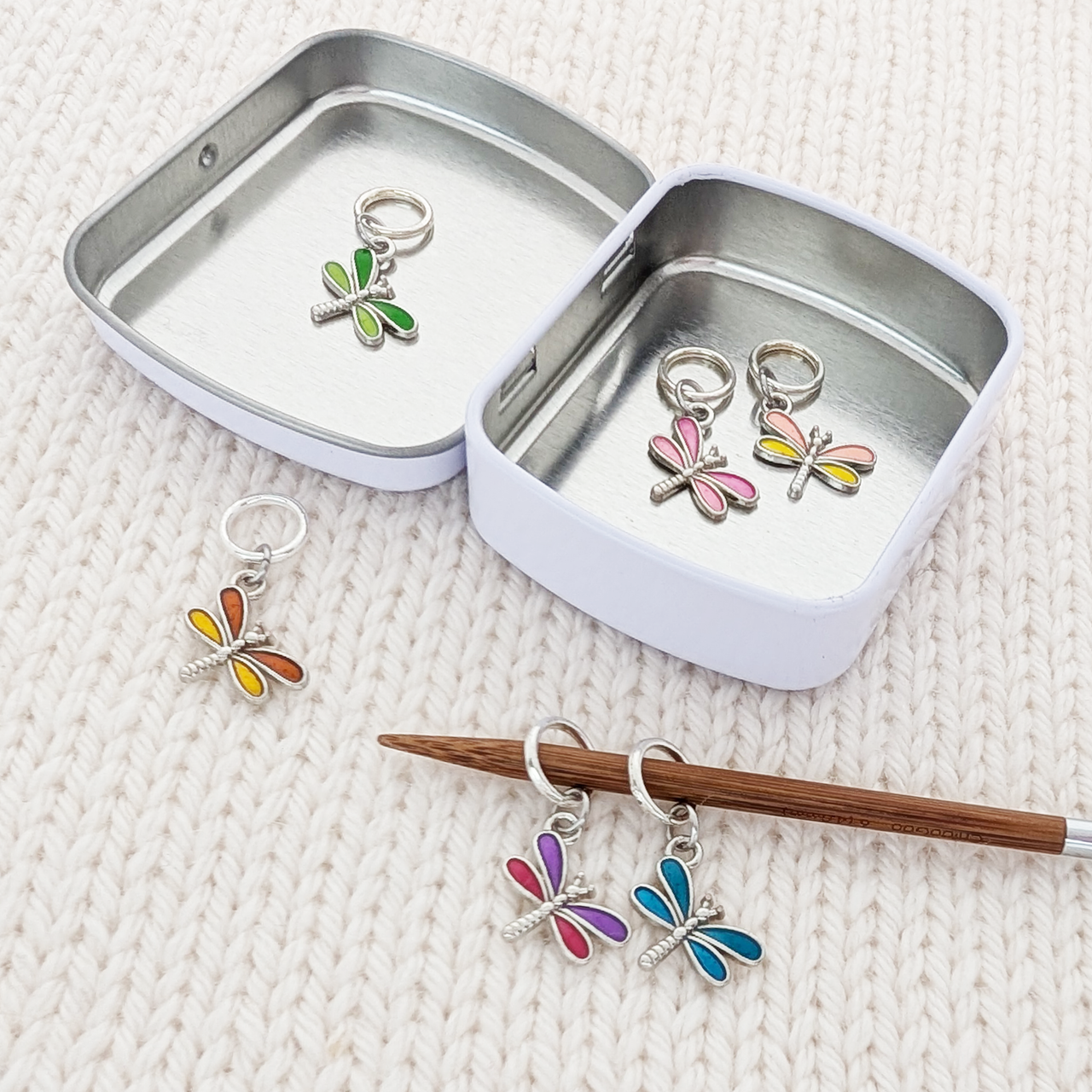Set of 6 Dragonfly Ring Stitch Markers for Knitting including storage tin, shown on knitting needle, by Pretty Warm Designs