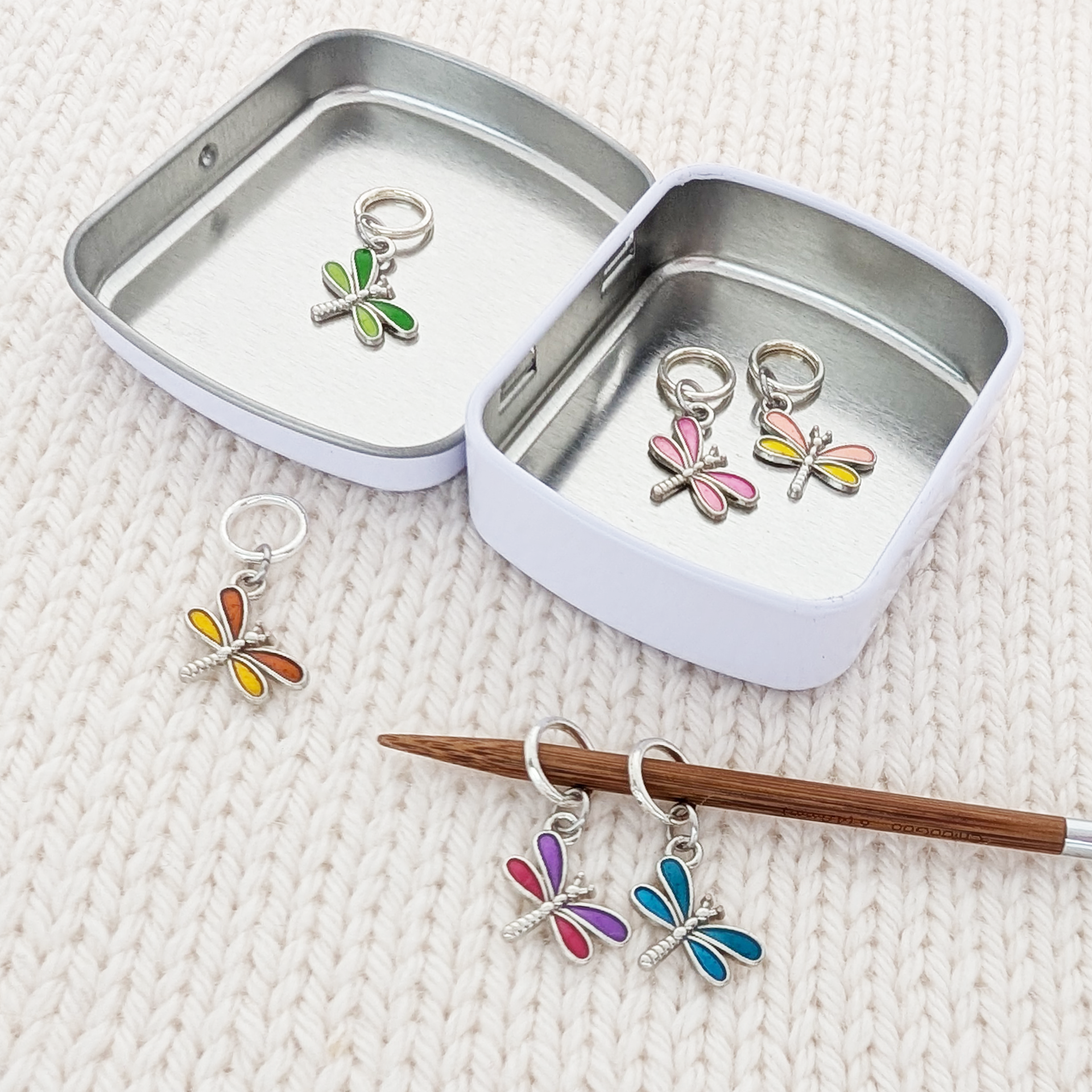 Set of 6 Dragonfly Ring Stitch Markers for Knitting including storage tin, shown on knitting needle, by Pretty Warm Designs