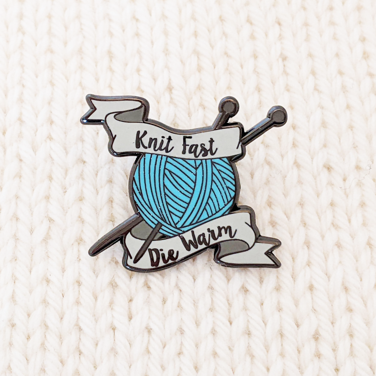 Knit Fast Die Warm sign with blue yarn ball and 2 knitting needles - enamel pin for project bags