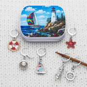 Nautical locking stitch markers for knitting and crochet displayed on white knitted fabric with a wooden needle and printed tin.