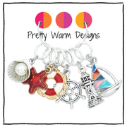 Pretty Warm Designs snag-free knitting ring markers with nautical charms, hanging together on a display holder.