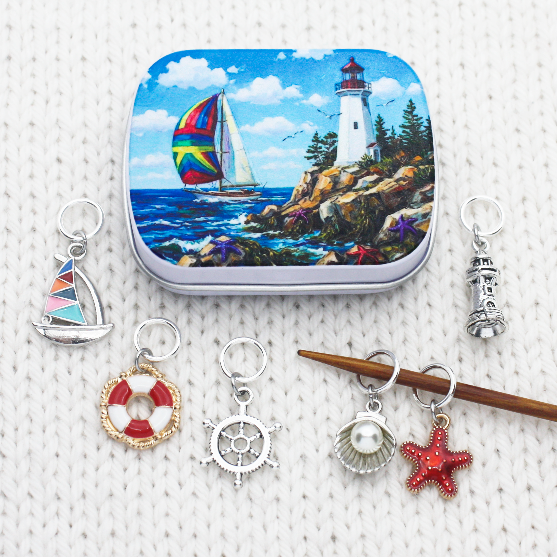 Snag-free nautical ring stitch markers for knitting displayed on white knit fabric with a wooden needle and printed tin.