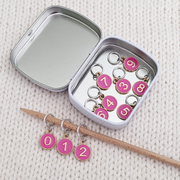 Dusky Rose Numbered Stitch Markers set of 10 with storage tin displayed on bamboo knitting needle and inside storage tin