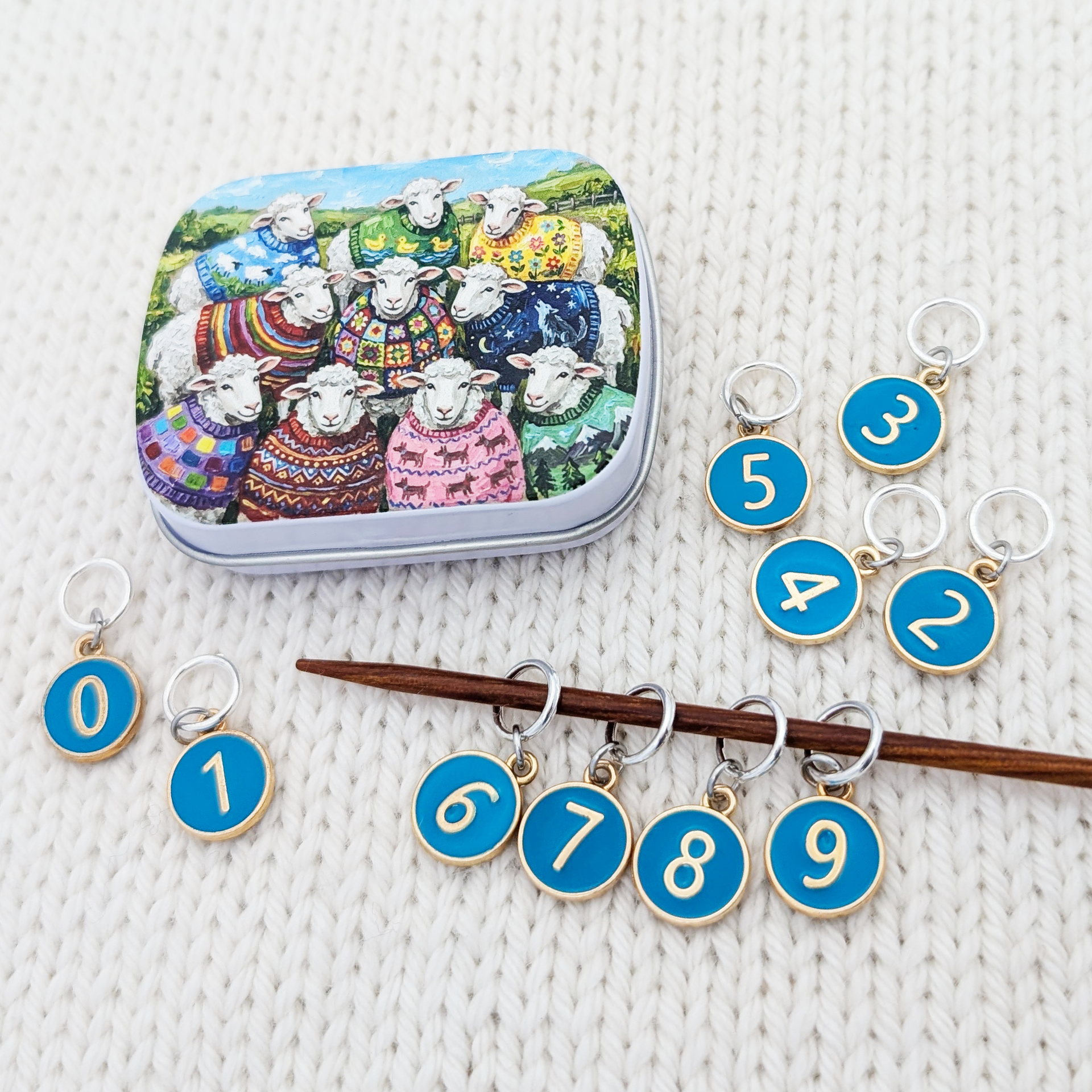 Set of 10 ring style stitch markers for knitting with charms numbered 0 - 9 with a custom artwork sheep sweater club hinged storage tin