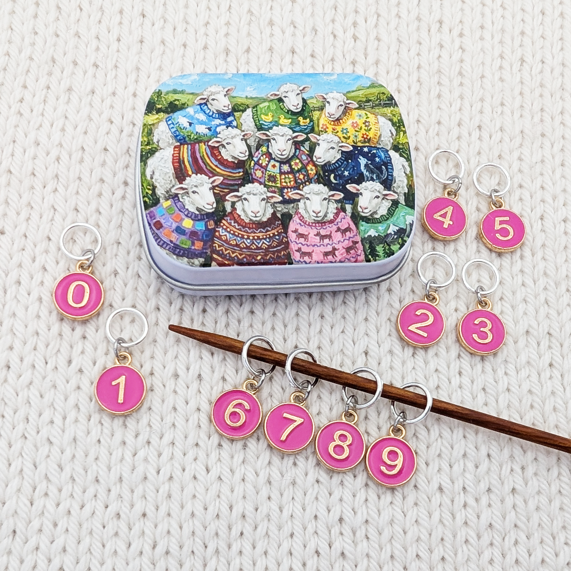 Set of 10 ring style stitch markers for knitting with charms numbered 0 - 9 with a custom artwork sheep sweater club hinged storage tin