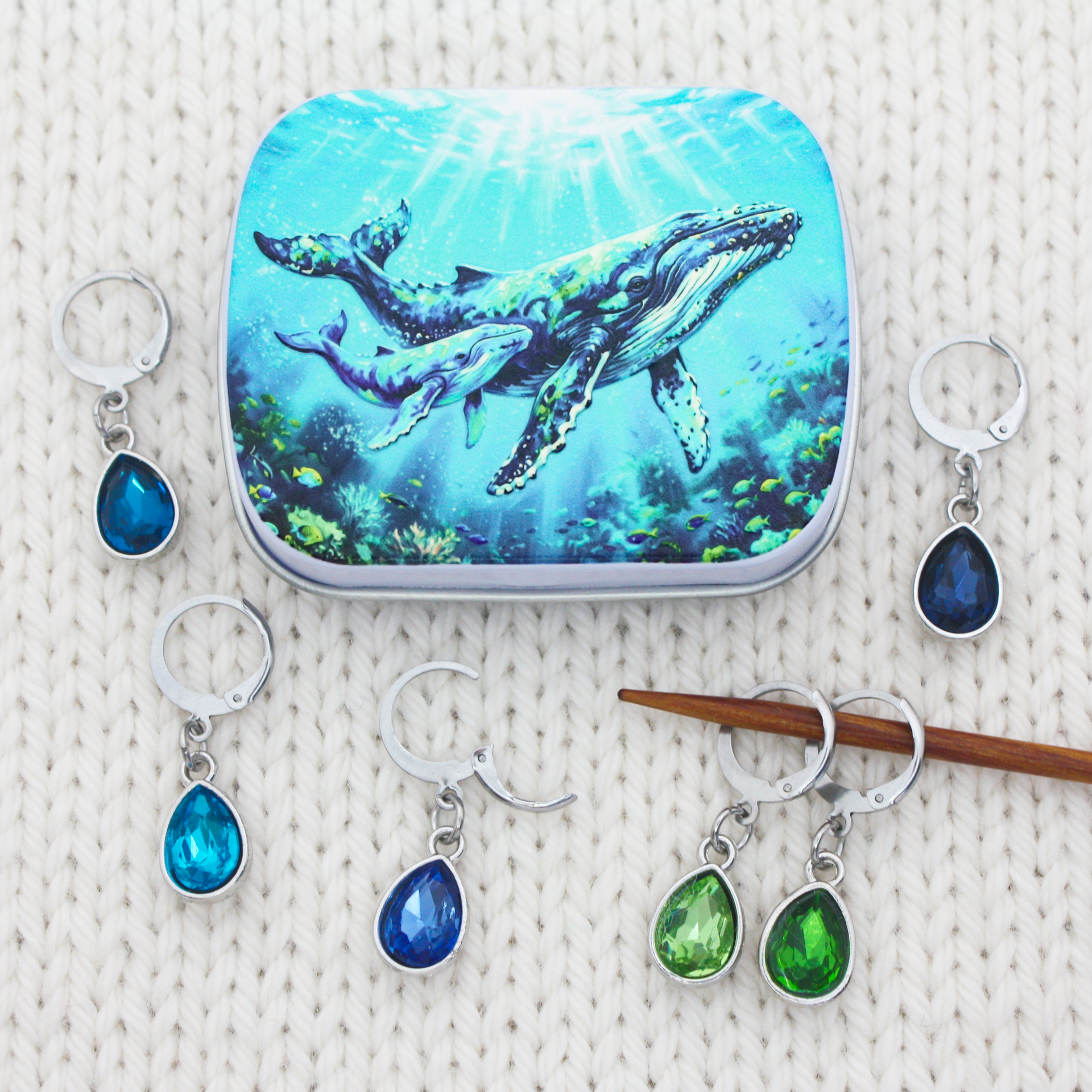 A yarn accessories notions tin with a humpback whale & calf print and six locking stitch holders