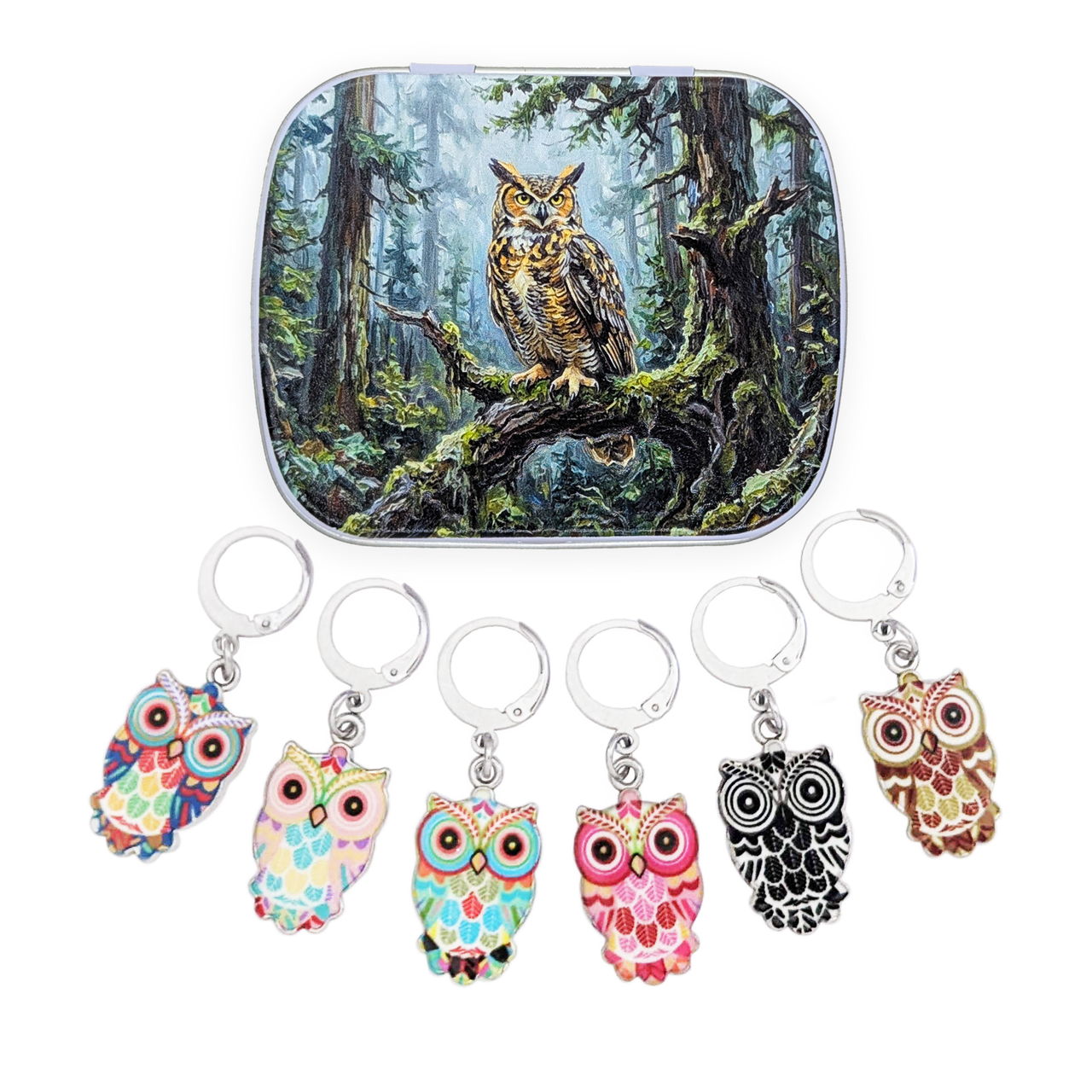 A metal tin with rounded corners featuring an illustration of a large owl perched in a forest, shown above six owl themed locking stitch markers for crochet or knitting in different colorful patterns on a white background.