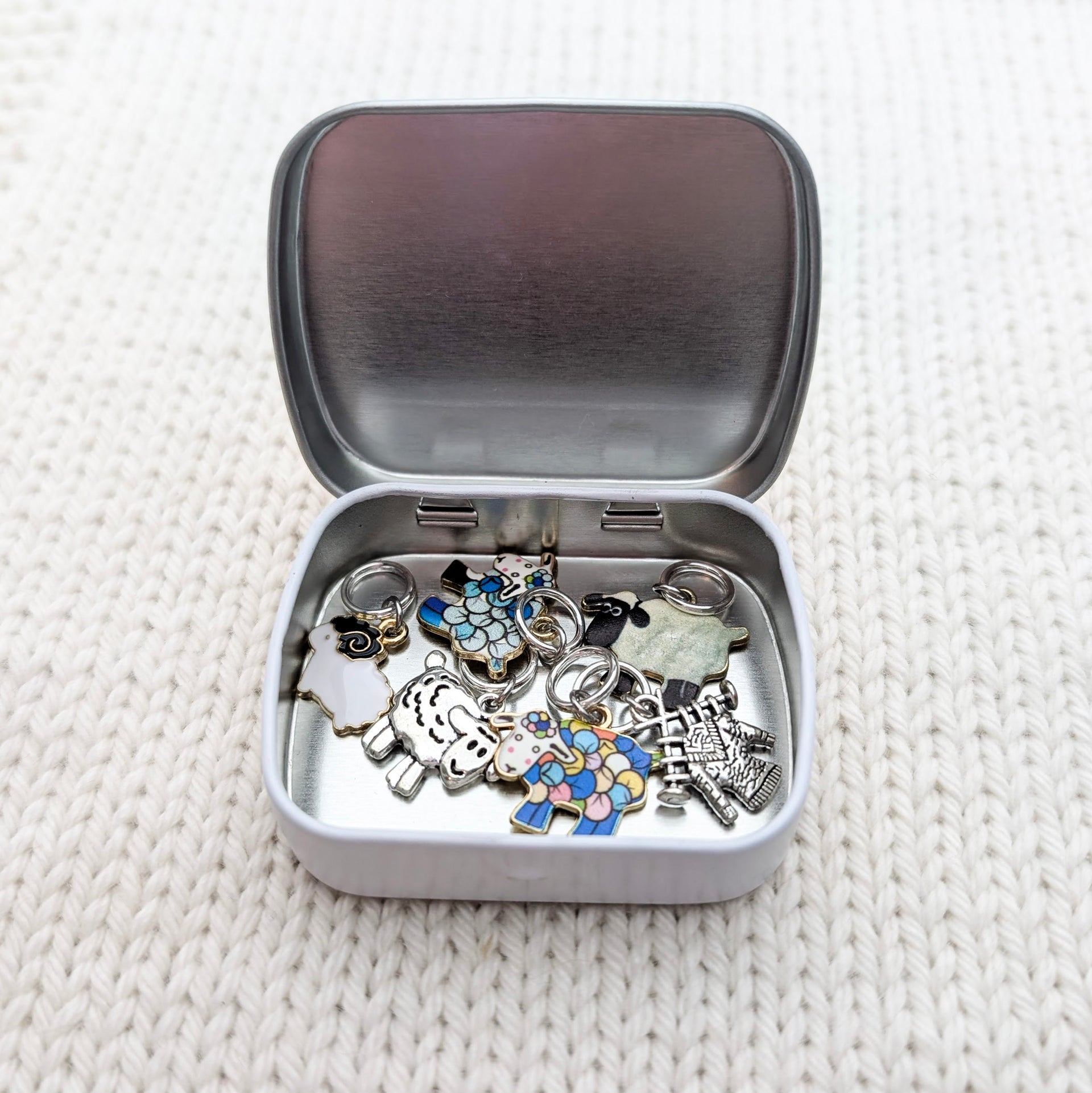 Pretty Warm Designs storage tin open showing six sheep knitting stitch markers — handmade gift for knitters