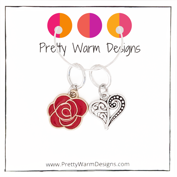 Two Valentine's Day themed knitting ring stitch markers, one red rose and one Tibetan antiqued silver filigree heart with Pretty Warm Designs text and logo