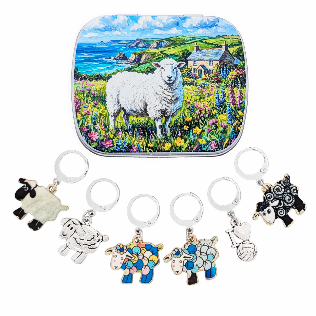 A sheep-themed locking stitch marker set displayed below a decorative tin featuring a painted white sheep in a flower field by the sea. The progress keepers include silver-tone and colorful enamel sheep charms, a black-and-white sheep charm, and an I love yarn charm.