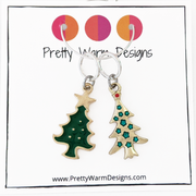 Two Christmas tree ring stitch markers, one green with gold edging and one gold with stars