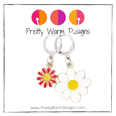 Two enamel charm crochet locking stitch markers with one white and one red daisy with Pretty Warm Designs text and logo