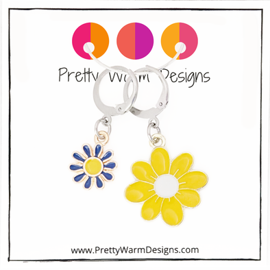 Two enamel charm crochet locking stitch markers with one yellow and one blue daisy with Pretty Warm Designs text and logo