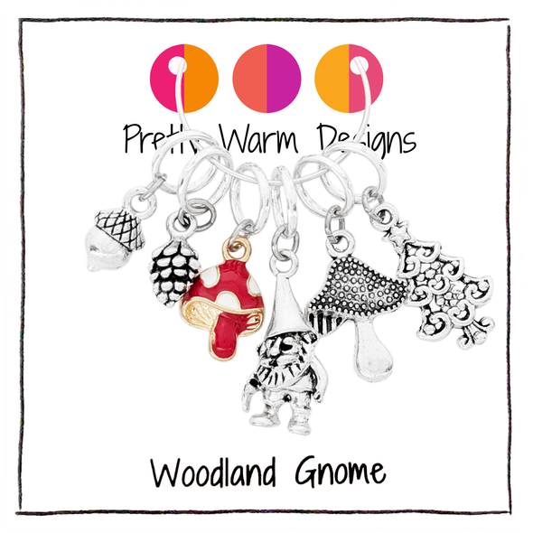 Set of six stitch markers for knitting, including a red enamel toadstool, as well as an antique silver acorn, toadstool, woodland gnome, pine cone and Christmas tree sold by Pretty Warm Designs Inc.