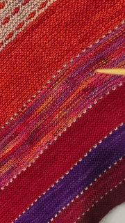 Video of six enamel butterfly charm snag free ring stitch markers in red, yellow, green, blue, pink and purple held on knitting needle in a woman's hand with an orange, red, purple and grey knitted shawl in the background by Pretty Warm Designs