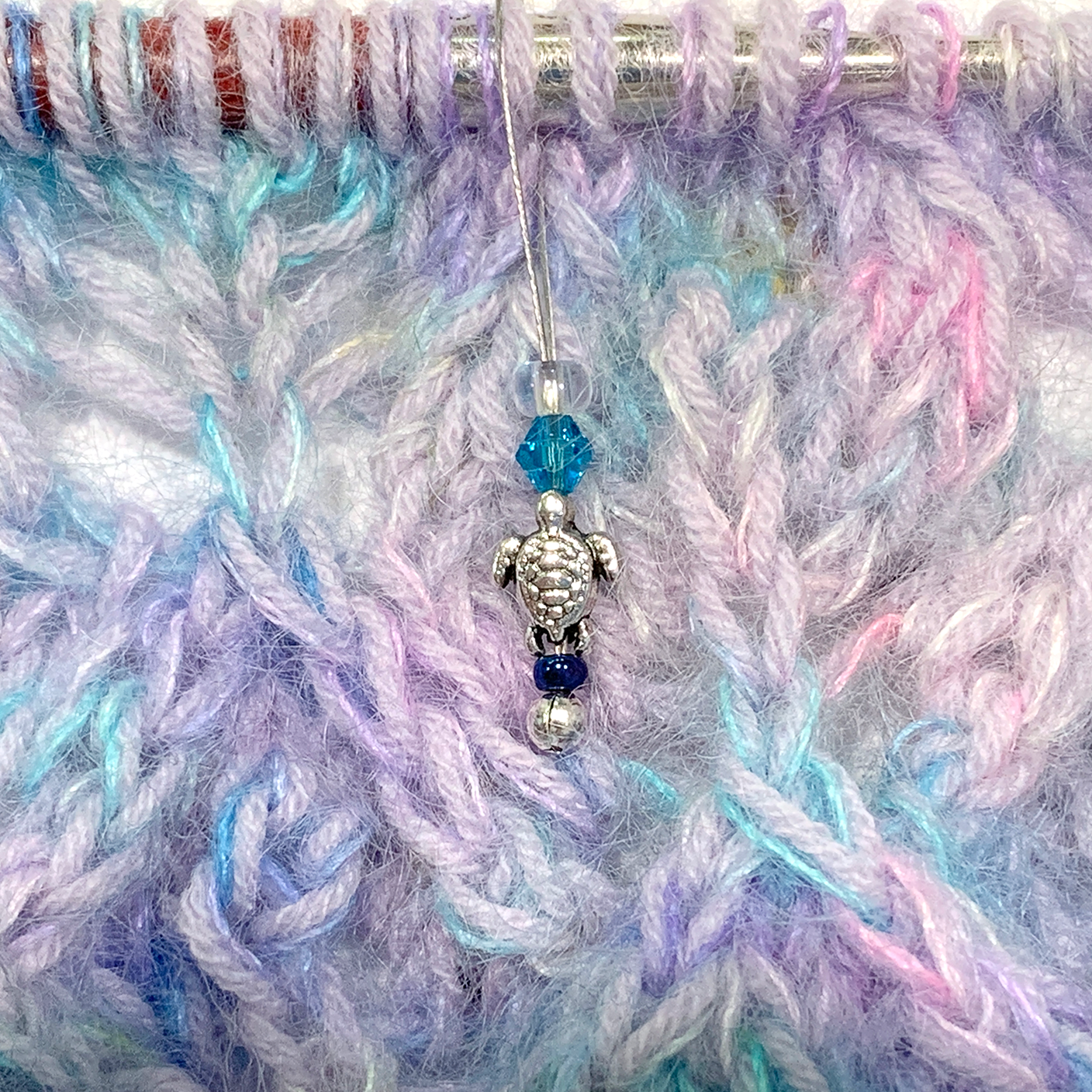 Small silver turtle bead, turquoise crystal bead, glass seed bead stitch markers on lace knitting by Pretty Warm Designs
