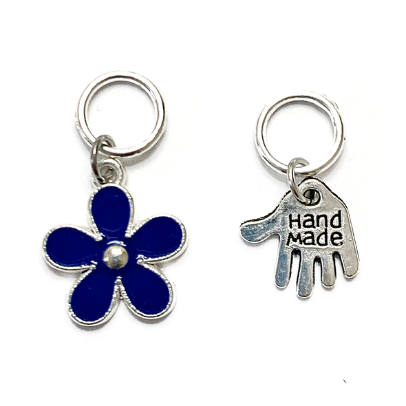 Two knitting stitch markers include one blue flower and one silver plated hand stamped with Hand Made charm by Pretty Warm Designs