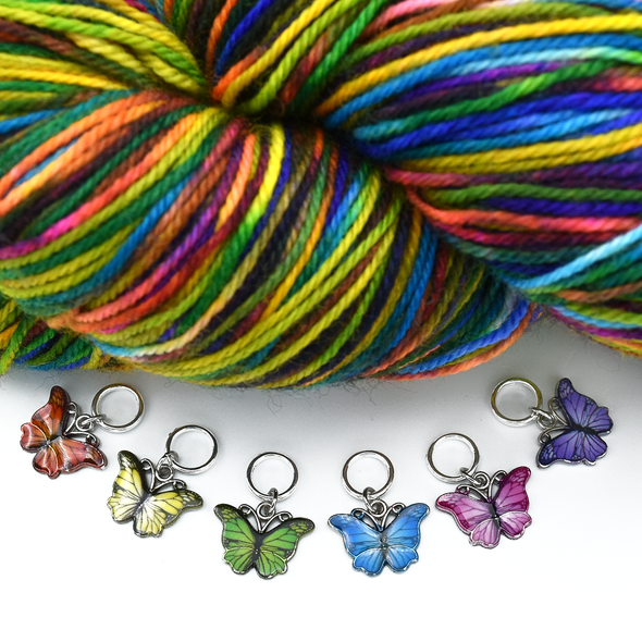 Set of six enamel butterfly charm snag free ring stitch markers in red, yellow, green, blue, pink and purple with skein of colourful variegated yarn for knitting by Pretty Warm Designs